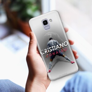 K&ouml;nnte beinhalten: Eine wei&szlig;e Handyh&uuml;lle mit einem grau-wei&szlig;en Bild eines Fu&szlig;ballspielers in einem wei&szlig;en Trikot mit der Nummer 7 auf dem R&uuml;cken. Der Text "CRISTIANO RONALDO" ist in Schwarz und Pink auf der H&uuml;lle aufgedruckt. Der Text "real madrid" ist in Schwarz am unteren Rand der H&uuml;lle aufgedruckt.