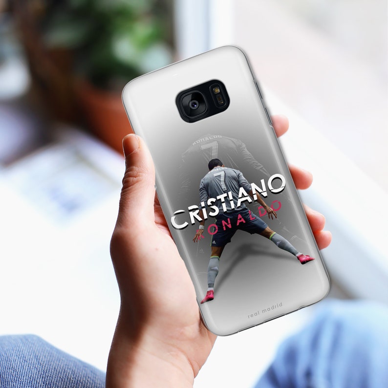 May include: White phone case with a photo of Cristiano Ronaldo in a soccer uniform. The text "Cristiano Ronaldo" and "Real Madrid" are printed on the case.