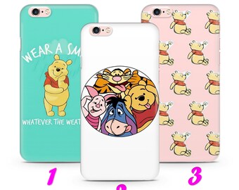 May include: Three different phone cases featuring Winnie the Pooh and his friends. The first case is turquoise with the text "Wear a Smile Whatever the Weather" and a picture of Winnie the Pooh. The second case is white with a circle featuring Winnie the Pooh, Tigger, Piglet, and Eeyore. The third case is pink with a repeating pattern of Winnie the Pooh.
