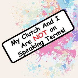 Puede incluir: Un letrero rectangular con borde negro y el texto "My Clutch And I Are NOT on Speaking Terms!" en negro y rojo. El fondo presenta salpicaduras de pintura coloridas en rosa, azul y verde.