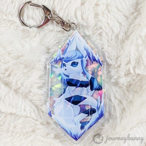 May include: A white and blue ice-type Pokemon character keychain with a holographic background. The character is in a crystal-shaped charm with a silver key ring.