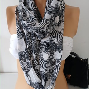 May include: White infinity scarf with a black and white zebra print.