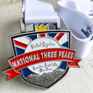 Może przedstawiać: Srebrny medal z czerwoną, białą i niebieską wstążką. Medal przedstawia tarczę z pasmem górskim i tekstem "National Three Peaks" oraz "Snowdon, Scafell Pike, Ben Nevis".