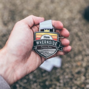 May include: A silver medal with a colourful design and the text "736m WHERNSIDE Yorkshire Dales".
