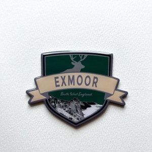 May include: A silver and green enamel pin with a deer silhouette and the text "EXMOOR South West England".