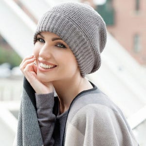 May include: A grey knit beanie with a ribbed cuff and a textured crown. The hat is made of a soft, woven material and features a classic, rounded shape that fits snugly around the head, providing a simple and clean look for any season.