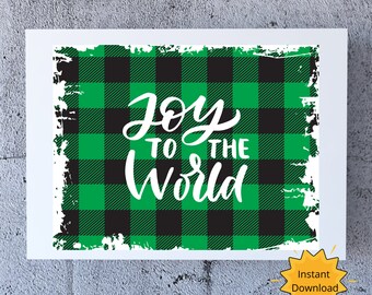 May include: A white framed print with a green and black plaid pattern background. The words "Joy to the World" are written in white script. A yellow starburst graphic with the words "Instant Download" is in the lower right corner.