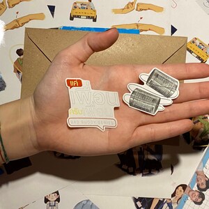 Op de afbeelding: Twee witte stickers met zwarte tekst en afbeeldingen. De eerste sticker zegt "แค่ พอน" en "Bad Buddy Series" in het Engels. De tweede sticker toont twee blikken die met een touwtje aan elkaar zijn verbonden.
