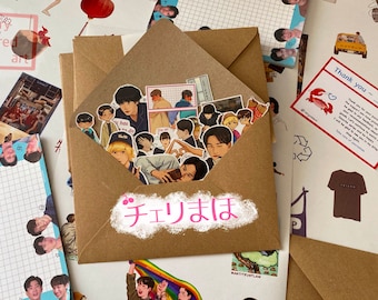 May include: A brown envelope with a white label that says "チェリまは" in Japanese. The envelope is filled with stickers of cartoon characters. The stickers are mostly of young men with different expressions and poses. There is also a thank you card with a red crab on it.