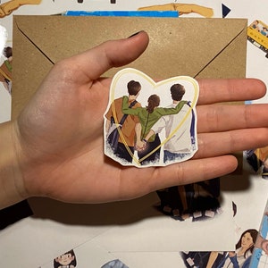 Op de afbeelding: Een sticker met drie mensen die samen in een hartvorm staan. De mensen zijn getekend in een cartoon-stijl en dragen casual kleding. De sticker is op een witte achtergrond.