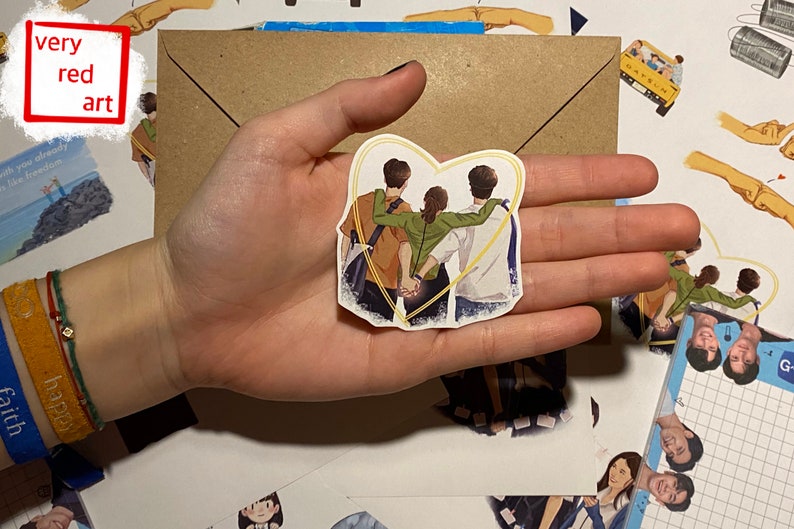 Op de afbeelding: Een sticker met drie mensen die samen in een hartvorm staan. De mensen zijn getekend in een cartoon-stijl en dragen casual kleding. De sticker is op een witte achtergrond.