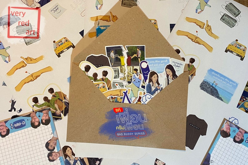 Op de afbeelding: Een bruine envelop gevuld met stickers en een T-shirt. De stickers tonen personages uit de Thaise BL-serie "Bad Buddy Series". De envelop heeft de titel en het logo van de serie op de voorkant.