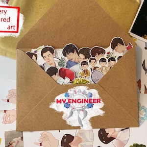 Puede incluir: Un sobre marrón lleno de pegatinas con ilustraciones de personas. El sobre tiene el texto "MY ENGINEER" y un diseño de atrapasueños. La esquina superior izquierda tiene el texto "very red art" en un recuadro rojo. Se ven otras ilustraciones.