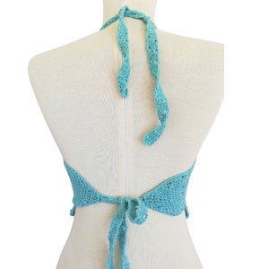 May include: A turquoise crochet halter top with a tie back. The top is made of a delicate, open-weave fabric.