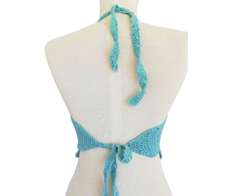 May include: A turquoise crochet halter top with a tie back. The top is made of a delicate, open-weave fabric.