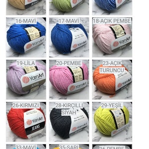 May include: A collection of yarn balls in various colours, including white, cream, light blue, light pink, yellow, orange, red, brown, grey, and green. Each ball has a label with the yarn brand name "YarnArt" and a number and colour name in Turkish.