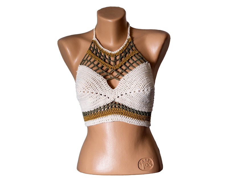 May include: White crochet halter top with green and brown accents. The top has a criss-cross design in the front and a scalloped bottom.