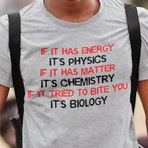 May include: A gray t-shirt with a humorous science-themed saying in red text: "If it has energy it's physics, if it has matter it's chemistry, if it tried to bite you it's biology."