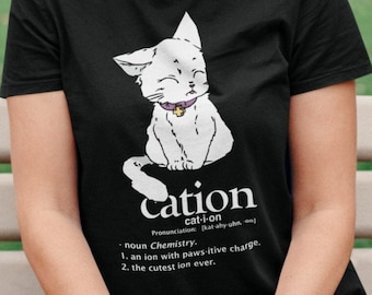 May include: Black t-shirt with a white cartoon cat wearing a purple collar with a gold charm. The shirt has the word "cation" written below the cat with a definition of the word.