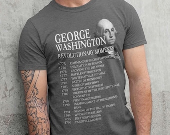 May include: A dark gray t-shirt with a portrait of George Washington and a list of his revolutionary moments from 1775 to 1796.