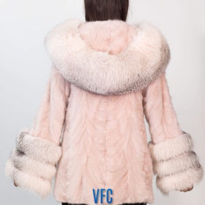 Puede incluir: Un abrigo de piel rosa con un gran cuello y pu&ntilde;os de piel blanca. El abrigo tiene un logotipo VFC en la espalda.