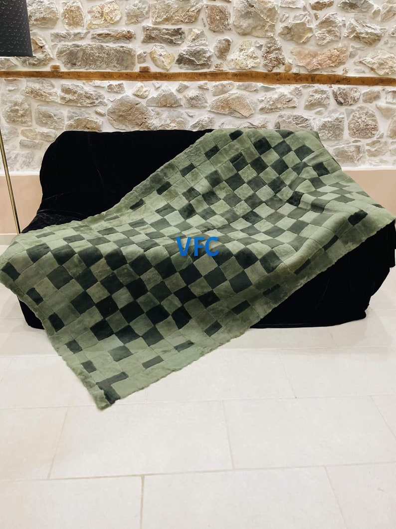 Pode incluir: Uma manta de l&atilde; xadrez verde e preta com as letras "VFC" em azul na manta.