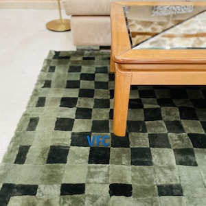 Pode incluir: Um tapete xadrez verde e preto com uma mesa de centro de madeira com tampo de vidro. O tapete &eacute; feito de um material macio e felpudo.