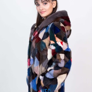 Puede incluir: Una chaqueta de piel de patchwork colorida con capucha. La chaqueta est&aacute; hecha de pieles de diferentes colores, incluyendo azul, rojo, verde y marr&oacute;n. La chaqueta tiene un logotipo de VFC en la parte inferior.