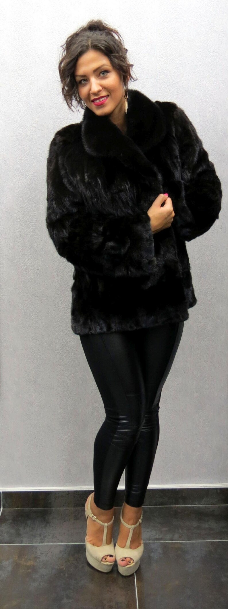 Puede incluir: Una mujer con un abrigo de piel negro y leggings negros con tacones de plataforma beige.