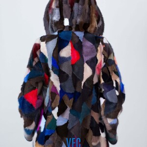 Puede incluir: Una chaqueta de piel de patchwork colorida con capucha. La chaqueta est&aacute; hecha de diferentes piezas de piel de colores cosidas juntas en un patr&oacute;n aleatorio. La chaqueta tiene un logotipo bordado en azul que dice "VFC" en la espalda.
