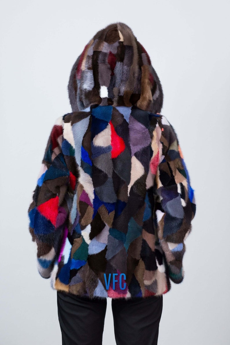 Puede incluir: Una chaqueta de piel de patchwork colorida con capucha. La chaqueta est&aacute; hecha de diferentes piezas de piel de colores cosidas juntas en un patr&oacute;n aleatorio. La chaqueta tiene un logotipo bordado en azul que dice "VFC" en la espalda.