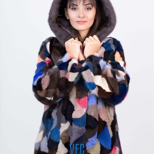Puede incluir: Una chaqueta de piel de patchwork colorida con capucha. La chaqueta est&aacute; hecha de pieles de diferentes colores, incluyendo marr&oacute;n, negro, azul y rosa. La chaqueta tiene un logotipo de VFC en la parte delantera.