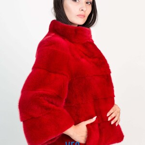 Peut inclure: Une veste en fourrure rouge avec un col montant et un logo VFC sur la poche.