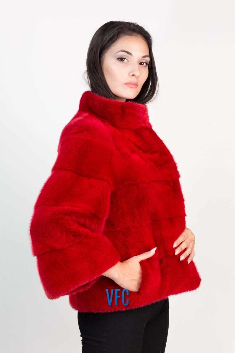 Peut inclure: Une veste en fourrure rouge avec un col montant et un logo VFC sur la poche.