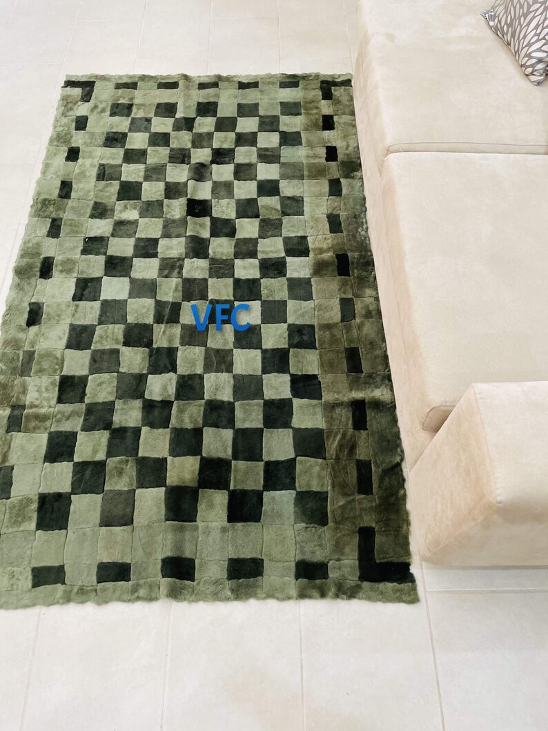 Pode incluir: Um tapete xadrez verde e preto com uma borda ligeiramente desfiada. O tapete &eacute; feito de um material macio e felpudo e tem um design &uacute;nico de patchwork.