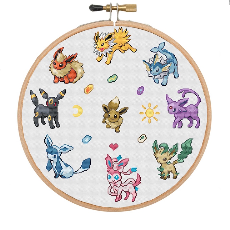 May include: A white embroidery hoop with a colorful cross-stitch design featuring various Pokemon characters, including Pikachu, Eevee, and others. The characters are surrounded by small, colorful details.