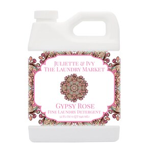 May include: A white plastic jug with a pink and orange label. The label features a mandala design and the text "JULIETTE & IVY THE LAUNDRY MARKET GYPSY ROSE FINE LAUNDRY DETERGENT 32 FL. OZ 1 QT/946 MLJ".