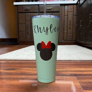Może przedstawiać: Jasnozielony kubek ze stali nierdzewnej z czarno-czerwonym wzorem Minnie Mouse i imieniem "Rhylee" napisanym czarnymi literami.