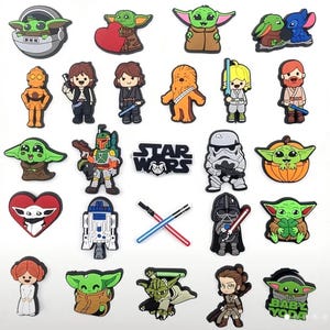 May include: A set of 25 colorful Star Wars themed shoe charms featuring characters like Yoda, Baby Yoda, Chewbacca, Darth Vader, and Stormtroopers. The charms are made of rubber and have a variety of designs.