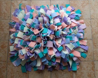 May include: A colorful sensory mat made of soft fabric in shades of pink, purple, blue, and white. The mat is made of many small pieces of fabric that are sewn together to create a textured surface.