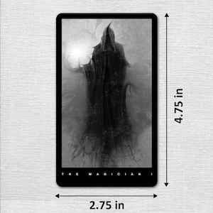 May include: Black and white tarot card featuring a hooded figure with a glowing orb in the background. The card is titled "The Magician". The card measures 4.75 inches by 2.75 inches.