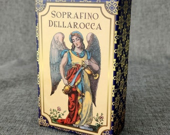 May include: A box of playing cards with a blue and gold design. The box features an illustration of an angel with wings, holding two jugs. The text "Soprafino Dellarocca" is printed on the front of the box.