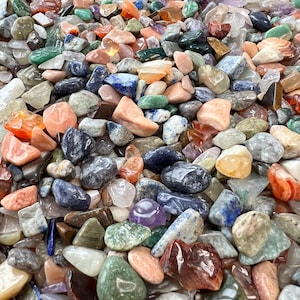 May include: A large collection of tumbled stones in various colours and shapes, including green, blue, red, orange, and brown. The stones are smooth and polished, and they are perfect for use in crafts, jewellery making, or as decorative accents.
