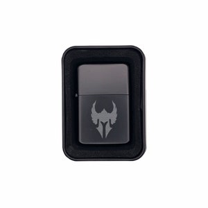 May include: A black lighter with a silver winged helmet design in a black box.