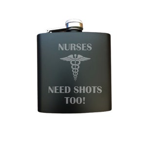 May include: Black metal flask with a silver top and the text "NURSES NEED SHOTS TOO!" engraved on the front. The flask also features a silver medical symbol.