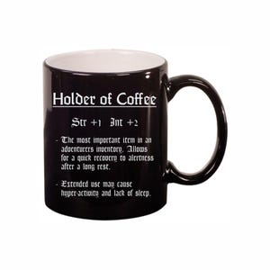 May include: Black coffee mug with the text "Holder of Coffee" in a gothic font. The mug also includes text that reads "Str +1 Int +2" and a description of the item's effects. The interior of the mug is white.