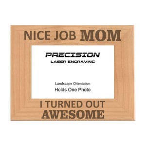 May include: A wooden picture frame with the text "NICE JOB MOM" at the top and "I TURNED OUT AWESOME" at the bottom. The frame is engraved with the text "PRECISION LASER ENGRAVING" and states "Landscape Orientation Holds One Photo".