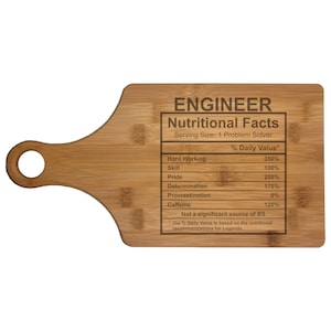May include: A brown wooden cutting board with a handle. The board has a humorous nutritional facts label for engineers, listing things like hard working, skill, pride, determination, procrastination, and caffeine.