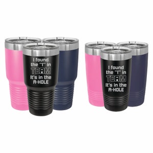May include: Set of four stainless steel tumblers with a black, pink, and blue color scheme. The tumblers feature a humorous saying: "I found the "I" in TEAM. It's in the A-HOLE."