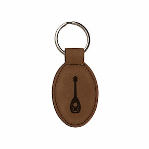 May include: Brown leather keychain with a silver key ring and an engraved silhouette of a mandolin.